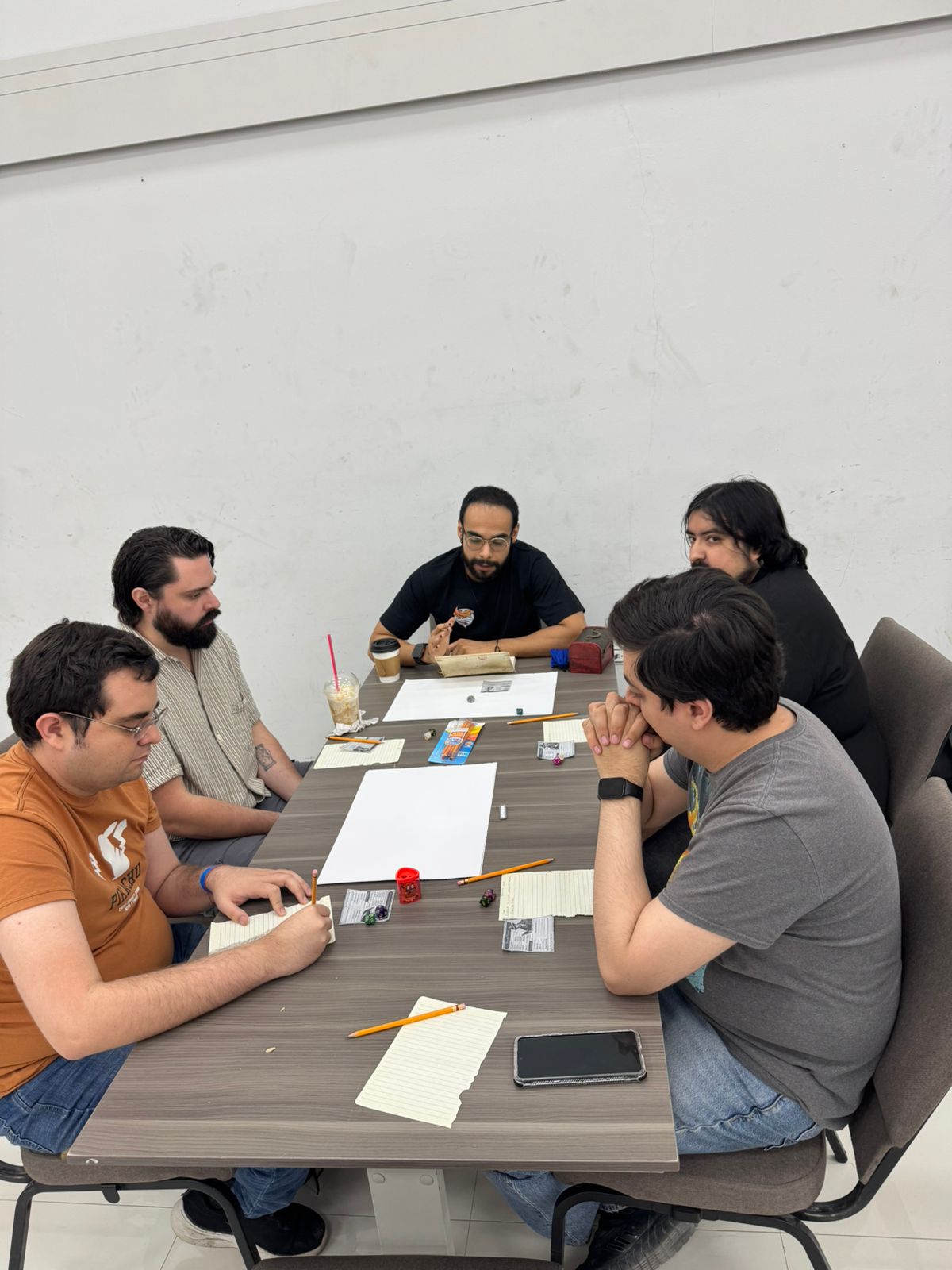 Jugadores reunidos en una mesa de rol con hojas, dados y material de juego